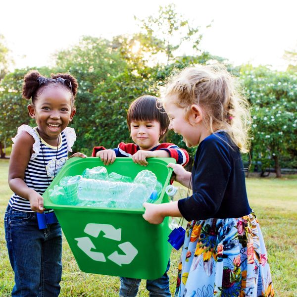 kids smiling holding recycling bin