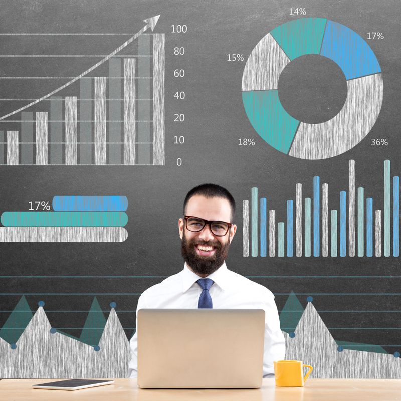 Portrait of successful businessman with laptop in front of financial data