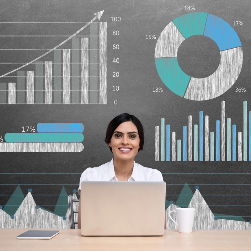 Successful businesswoman using laptop in front of financial report