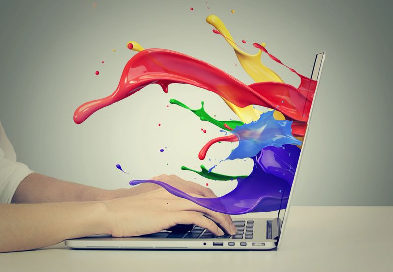 Closeup portrait of business woman's hands on keyboard using laptop with colorful splashes, liquid effect out of monitor screen computer display  isolated on gray background. Creative business concept