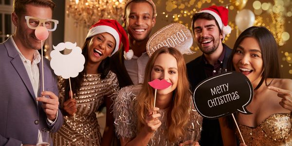 Friends and coworkers gather for a group photo using holiday props