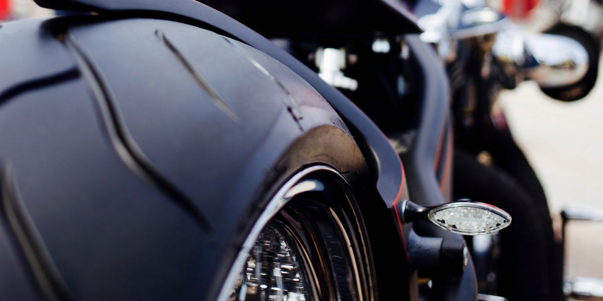 Close-up of a motorcycle's rear tire and chain with blurred background.