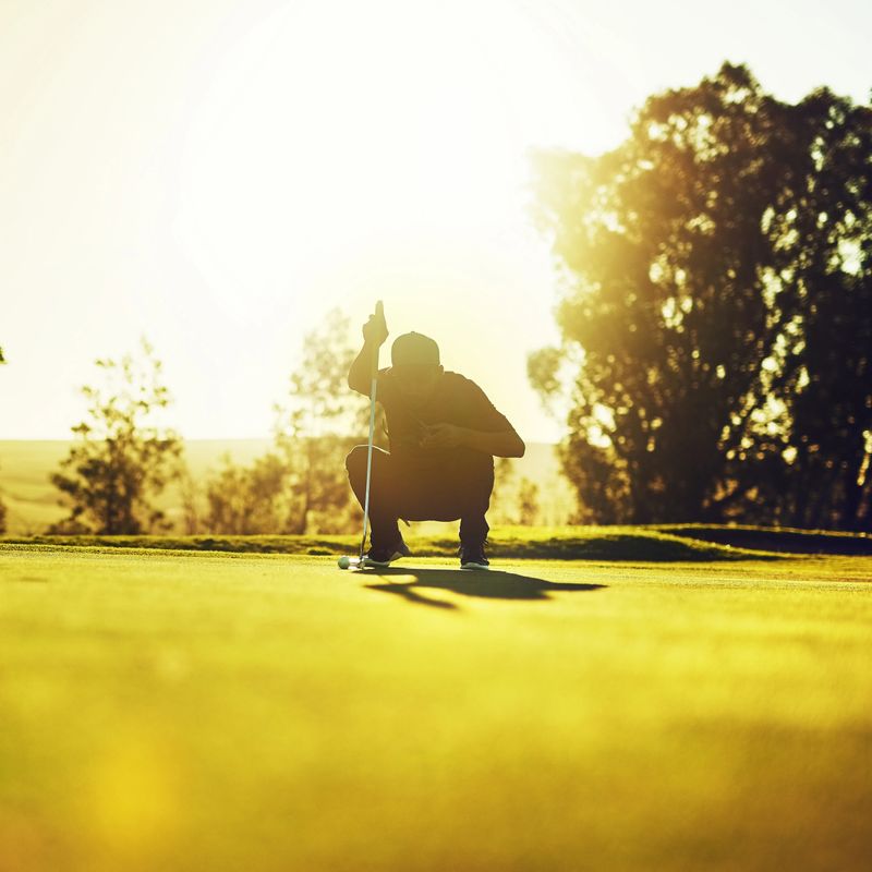 Shot of a young man eyeing up the putt during a round of golf