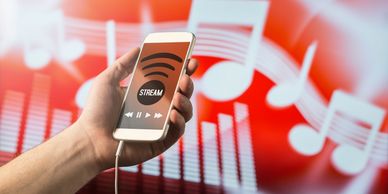 Person holding smartphone streaming music with headphones.