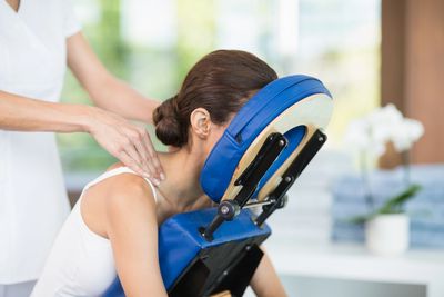 Woman receiving a shoulder massage on a massage chair with blue face support.
