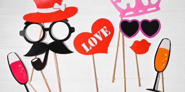 Photo booth props including hats, glasses, lips, heart, and champagne glasses on sticks.