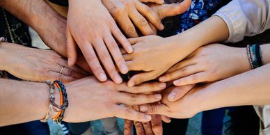 Multiple hands stacked together symbolizing unity and teamwork.