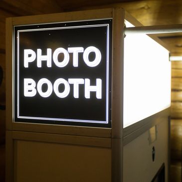 Illuminated photo booth sign in a wooden room.