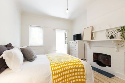 Bright, minimalist bedroom with white walls and yellow checkered blanket.