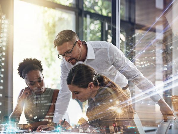 Three professionals collaborating over documents in a bright office with a cityscape overlay.