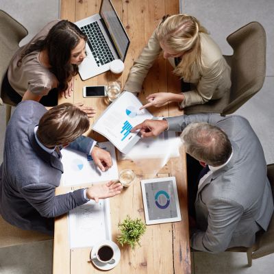 Four professionals discussing charts and data in a meeting.