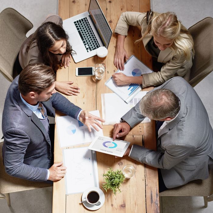 Business team discussing charts and graphs around a wooden table.