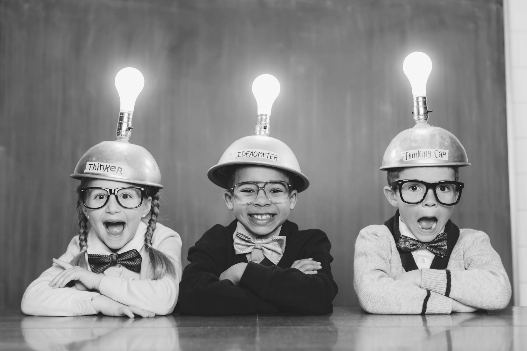 Three kids wearing light bulb helmets labeled as thinkers with excited expressions.