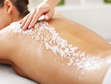 Person receiving a salt scrub massage on their back.