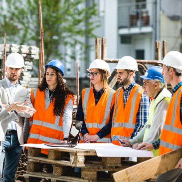 Group of construction workers discussing plans outdoors.