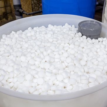 Large container filled with small white cylindrical tablets in an industrial setting.