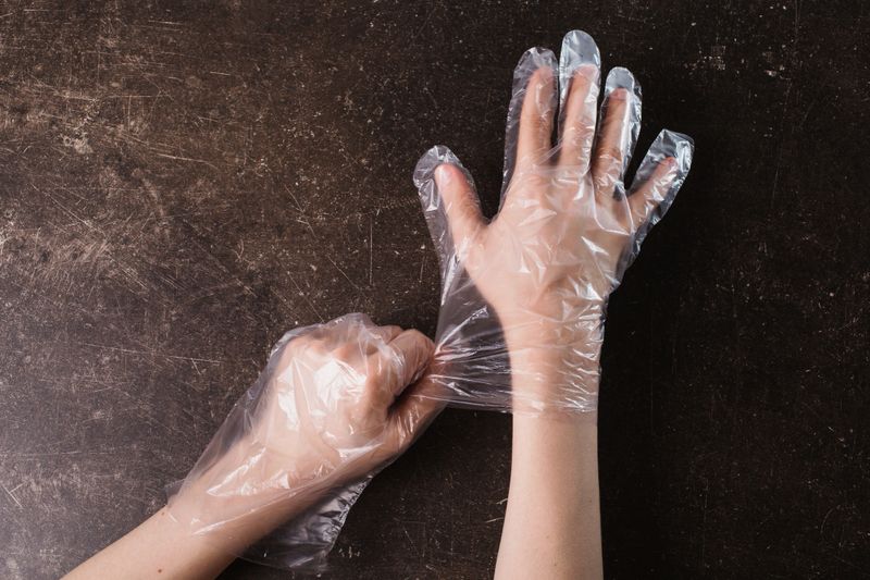 Hand in plastic hygienic gloves on a dark marble background. Tidy up the house. Do makeovers
