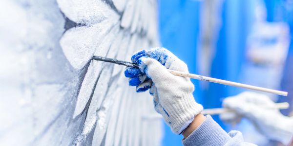 Painter's hands painting a mural with a brush.