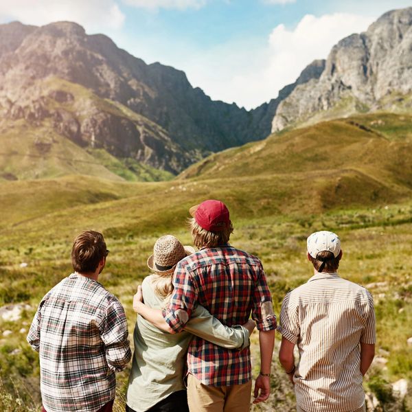 Four people admiring a mountainous landscape on a sunny day.
