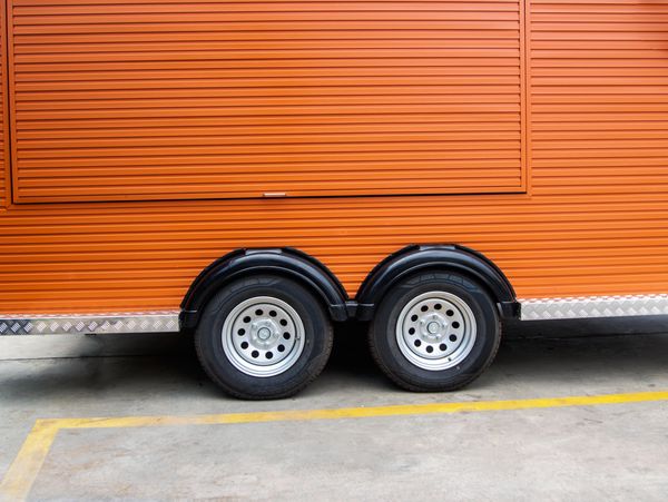 Close-up of dual wheels on an orange trailer with a ribbed exterior.