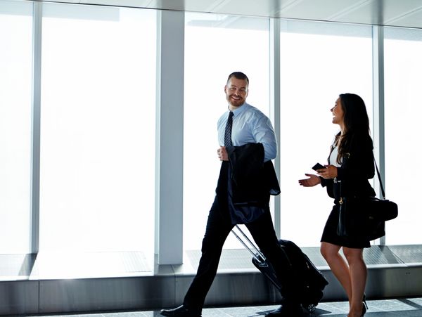 Two business professionals walking and talking in an airport terminal.