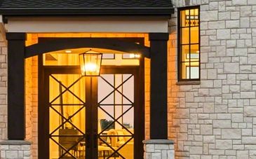 Warmly lit entrance with black-framed glass doors and stone walls.