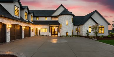 Elegant modern house with stone facade and warm lighting at sunset.