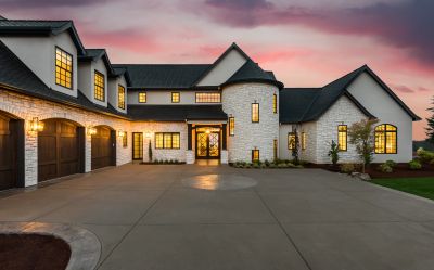 Large house with lit windows at sunset.
