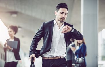 A businessman checking the time on his watch hurrying somewhere.