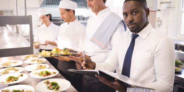 Chef and manager inspecting plated dishes in a professional kitchen.