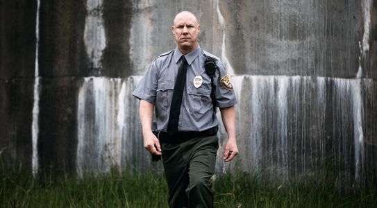 Security guard in blue uniform holding a walkie-talkie.
