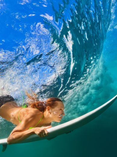 A woman rides a wave underwater on a surfboard.