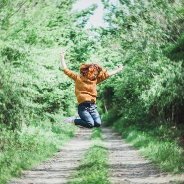 Person jumping on a forest path.