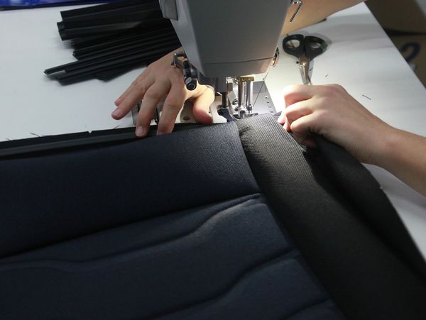 Illustrative seat upholstery being stitched on an industrial sewing machine