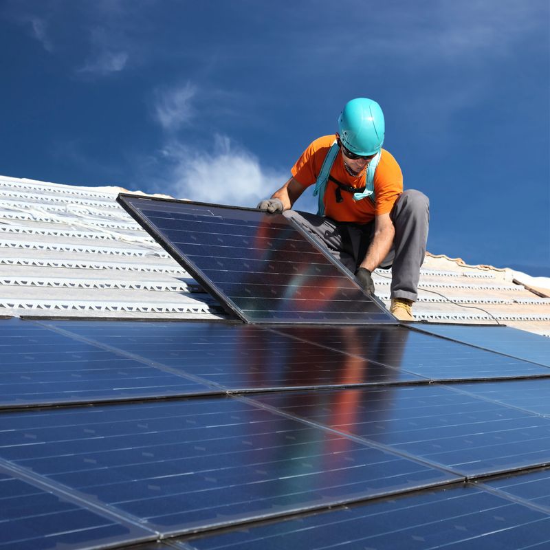 Man during intallation of alternative energy photovoltaic solar panels on roof