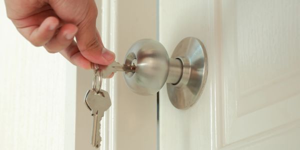 Hand inserting a key into a door lock.