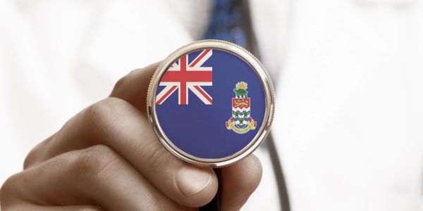 Hand holding a stethoscope with the Cayman Islands flag on the diaphragm.