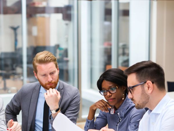 Three professionals discussing documents at a meeting.