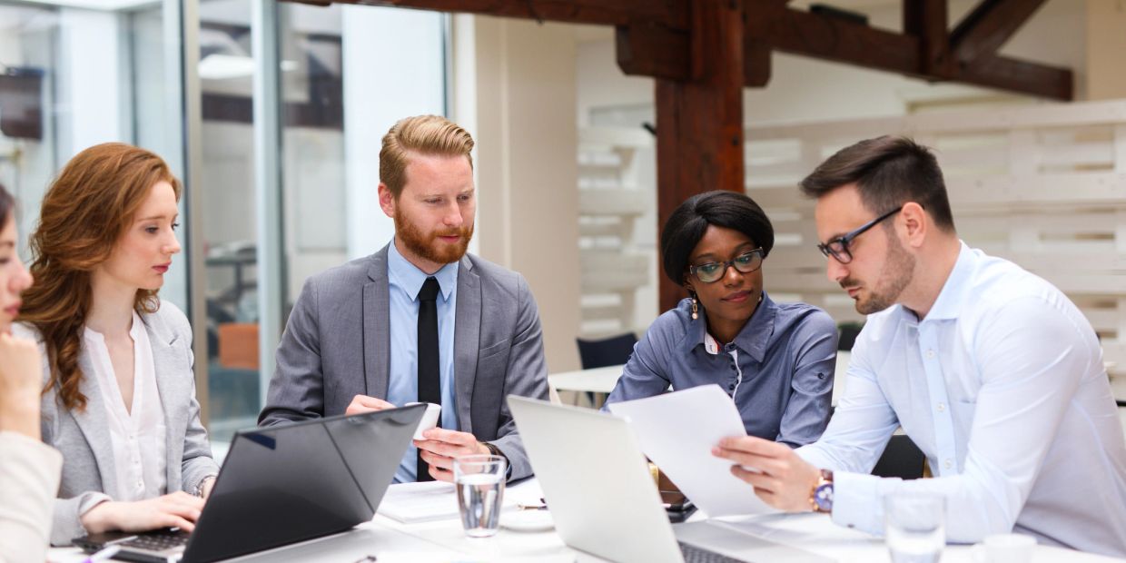 Colleagues discussing documents in a meeting.