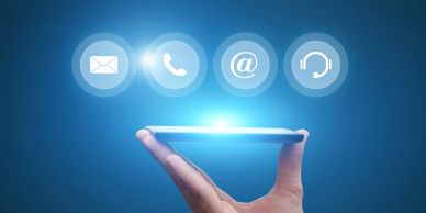 Hand holding a glowing smartphone with communication icons floating above it.