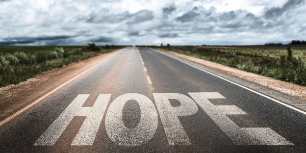 The word HOPE painted on a long empty road.