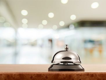 A shiny service bell on a countertop in a bright, blurred background setting.