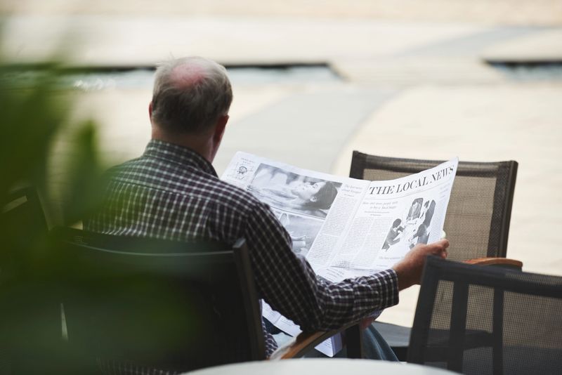 Rear view of man reading news in local newspaper
