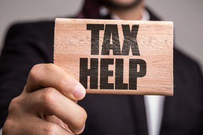 Man holding a wooden block with tax help written on it