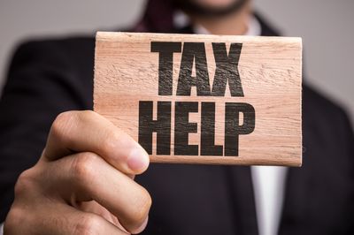 Man holding a wooden block with tax help written on it