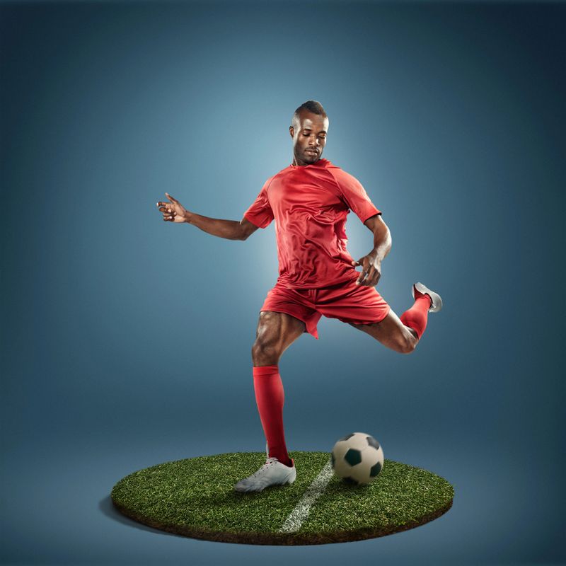 Game moment from soccer. The action takes place on a small round island covered with grass. Sportsman wears unbranded sport clothes