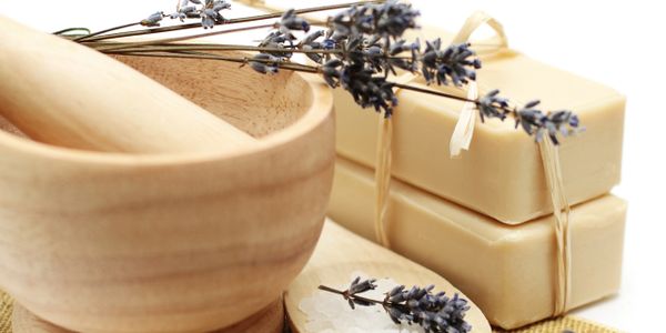 Wooden mortar and pestle with lavender and soap bars on cloth.