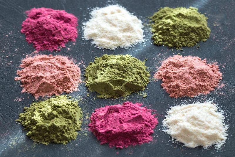 Various colorful superfood powders on dark background. Healthy food supplements, detox concept. Top view
