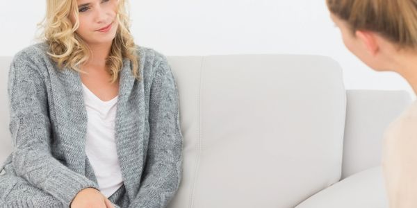 Two women in a therapy session, one talking and the other listening.