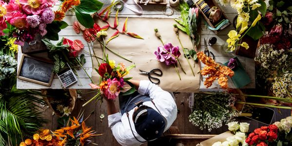Florist arranging vibrant flowers on a wooden table.